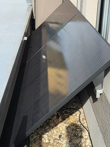 Zum Zeitpunkt der Aufnahme steht die Sonne im Osten. Die Edelstahlabdeckung sorgt für den Schatten. Die Panels sind so aufgestellt, dass im Winter bei flachstehender Sonne der Schatten im unteren Drittel bleibt. Eine höhere Aufständerung ohne Verschattung, würde die Fenster bis zur halben Höhe verdecken, was ich nicht wollte. Außerdem darf nichts an oder auf der Edelstahlabdeckung angebracht werden.